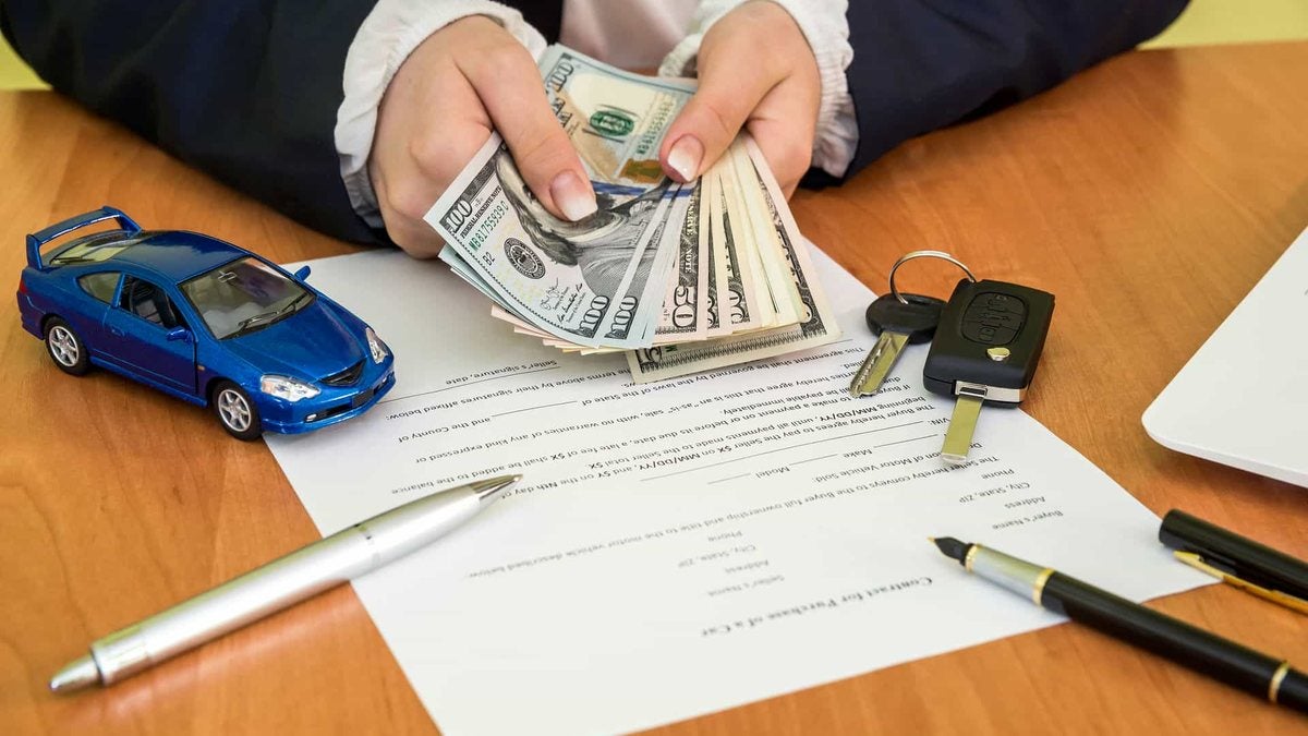 Car keys, cash and a vehicle purchase contract on a desk during a trade-in deal